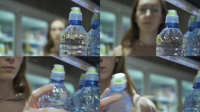 一名年轻女子走过，从超市的架子上拿了一瓶矿泉水