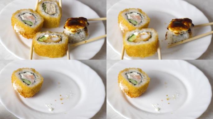 开胃的新鲜烤寿司是用筷子特写从不同侧面的盘子里取出的。日本寿司餐厅概念。寿司准备和交付。选择性聚焦