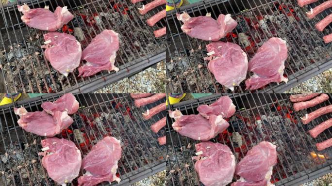 将生的红色猪肉块放在木炭烤架上。在乡下野餐。