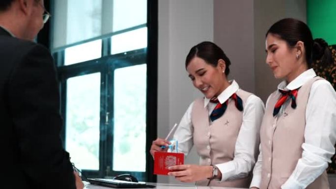 年轻的亚洲女商人检查手提箱的重量。两个人的背景。穿着西装的年轻女子在机场柜台办理护照手续。商务旅行生