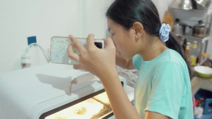 亚洲女孩在流媒体烤箱中倒水，并在家里的厨房为Tiktok制作病毒视频，社交媒体生活方式概念。
