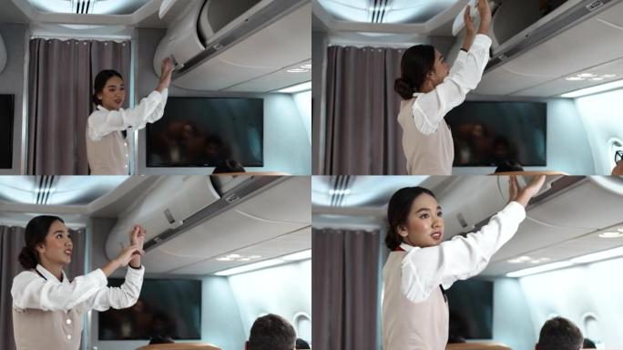 亚洲美丽的女乘务员关闭高架橱柜行李舱，以检查飞机起飞前乘客和飞机上的一群人的安全。航空公司概念。