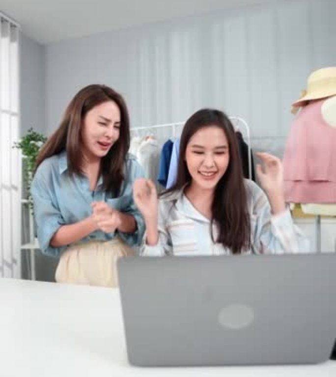 两名亚洲女性在完成服装在线销售的直播后，从在线客户那里获得了许多订单，在达到每日销售目标后表现出了喜