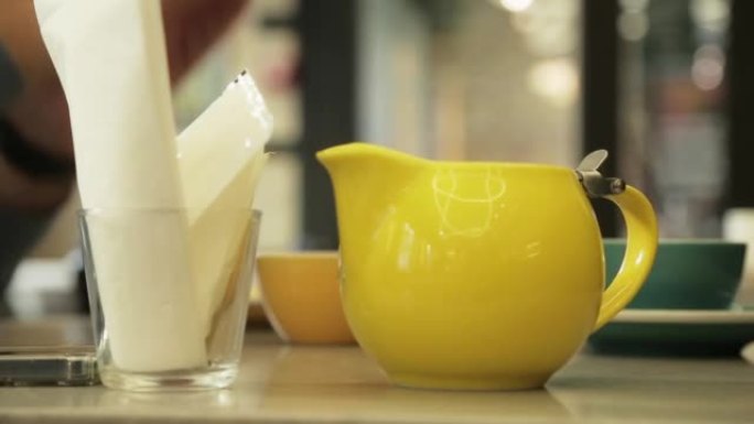 黄色牛奶壶水罐飘带咖啡起泡剂。水罐站在桌子上，咖啡制作车间
