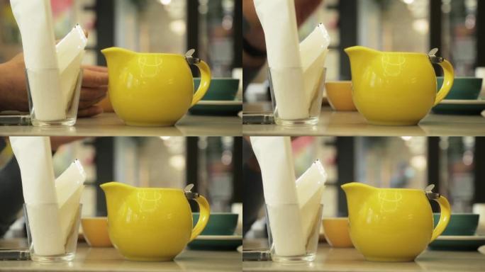 黄色牛奶壶水罐飘带咖啡起泡剂。水罐站在桌子上，咖啡制作车间