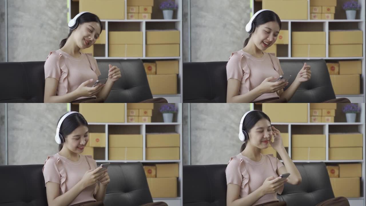 一个戴着耳机的年轻亚洲妇女可以在家里的沙发上愉快地听音乐。