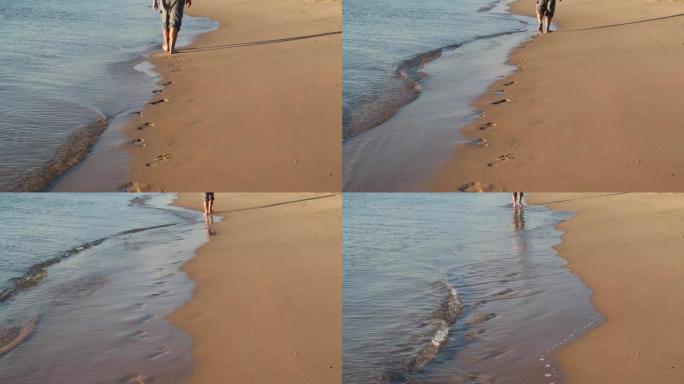 沿着海的边缘行走的人的脚在沙子上留下脚印
