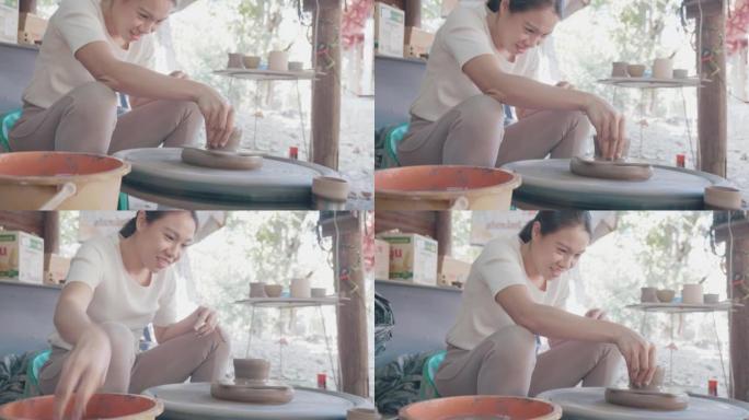 亚洲女性黏土艺术家在她的工作室里用旋转的陶器轮工作