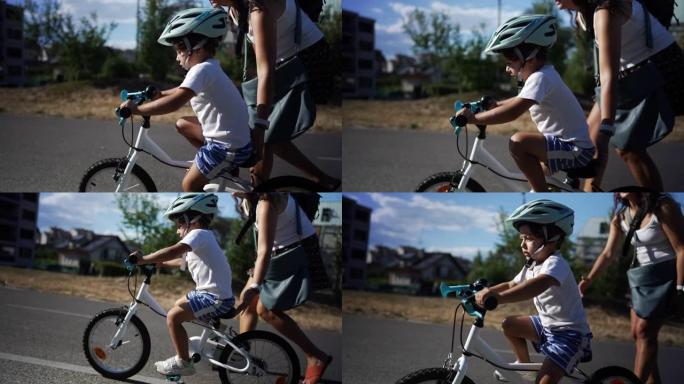 活跃的小男孩在阳光明媚的日子里和妈妈一起在外面学习骑自行车。在阳光明媚的日子里，孩子在父母的帮助下学