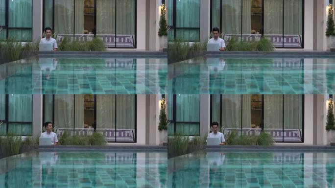 man working on laptop sitting by the pool