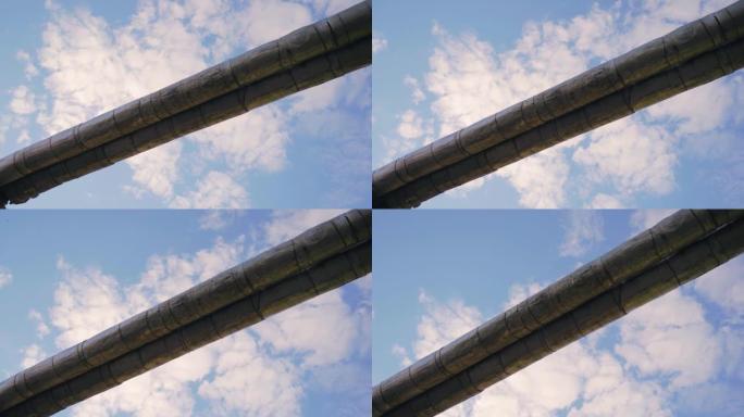 蓝天和云的背景下的两个旧管道。从下方拍摄，相机运动平稳