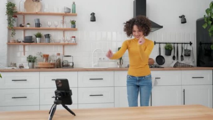 女人博主在智能手机摄像头上跳舞，为社交媒体录制视频