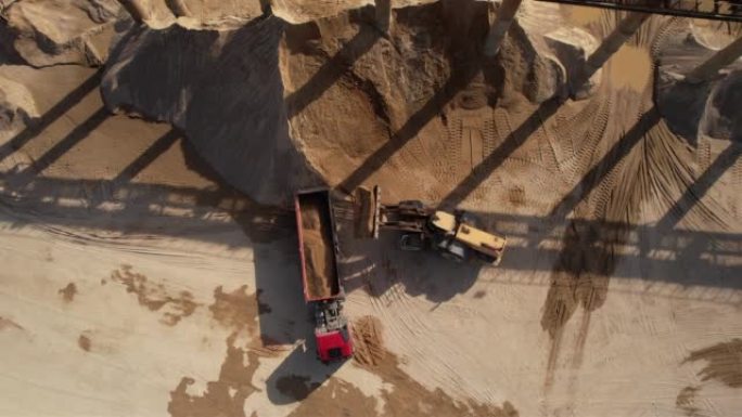 轮式装载机在露天矿的自卸车中装载沙子。露天矿土方工程前端装载机。