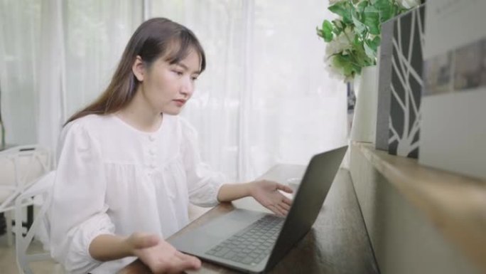 年轻女子在家使用笔记本电脑工作，面对工作问题时头疼。