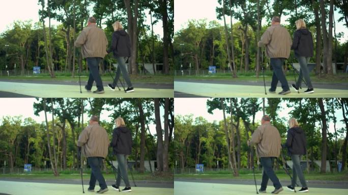 养老金领取者在公园里从事北欧散步。一个男人和一个女人用棍子走路来改善健康。