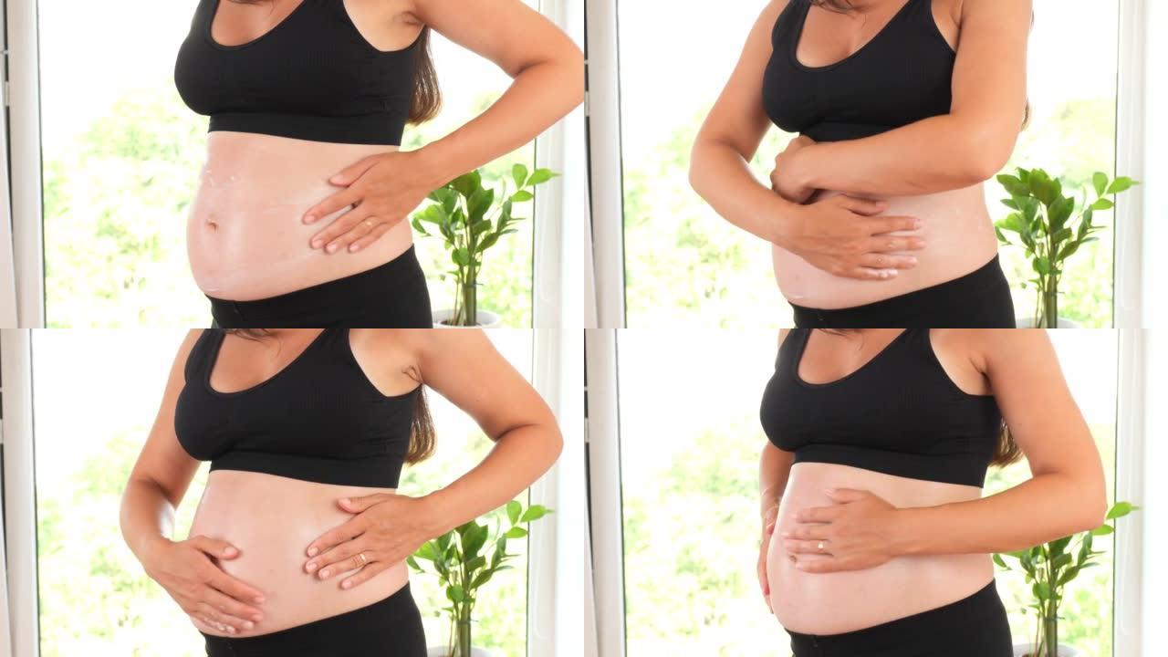 一个怀孕的女孩在她的肚子上涂上妊娠纹乳膏。