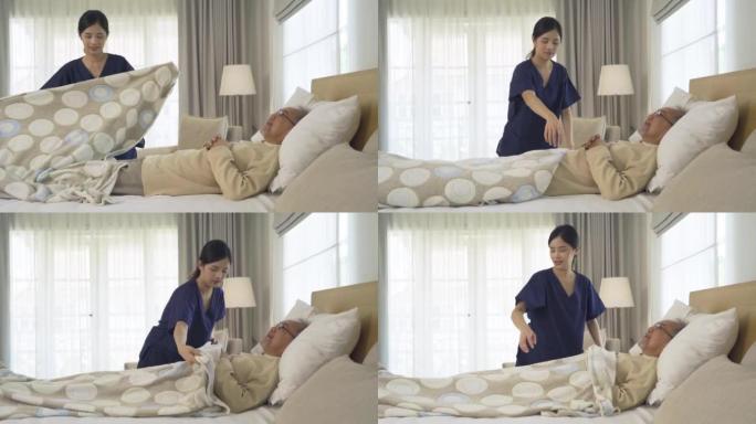 快乐的女人护士，女儿为生病的老年老年患者盖了毯子，躺在床上在家里的卧室或房子里接受医疗和保健治疗。亚