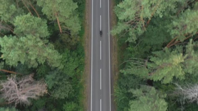 骑摩托车穿过森林路的人。摩托车手在乡村路线上骑摩托车。旅途中开车的人。旅途中骑自行车的人。自由和旅程