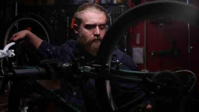 熟练的自行车修理工的特写镜头，观看山地自行车的后换挡器，使用在黑暗车库工作的车把换挡杆改变速度