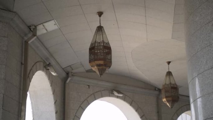 两盏铜图案的灯悬挂在敞开的拱门附近的瓷砖天花板上。