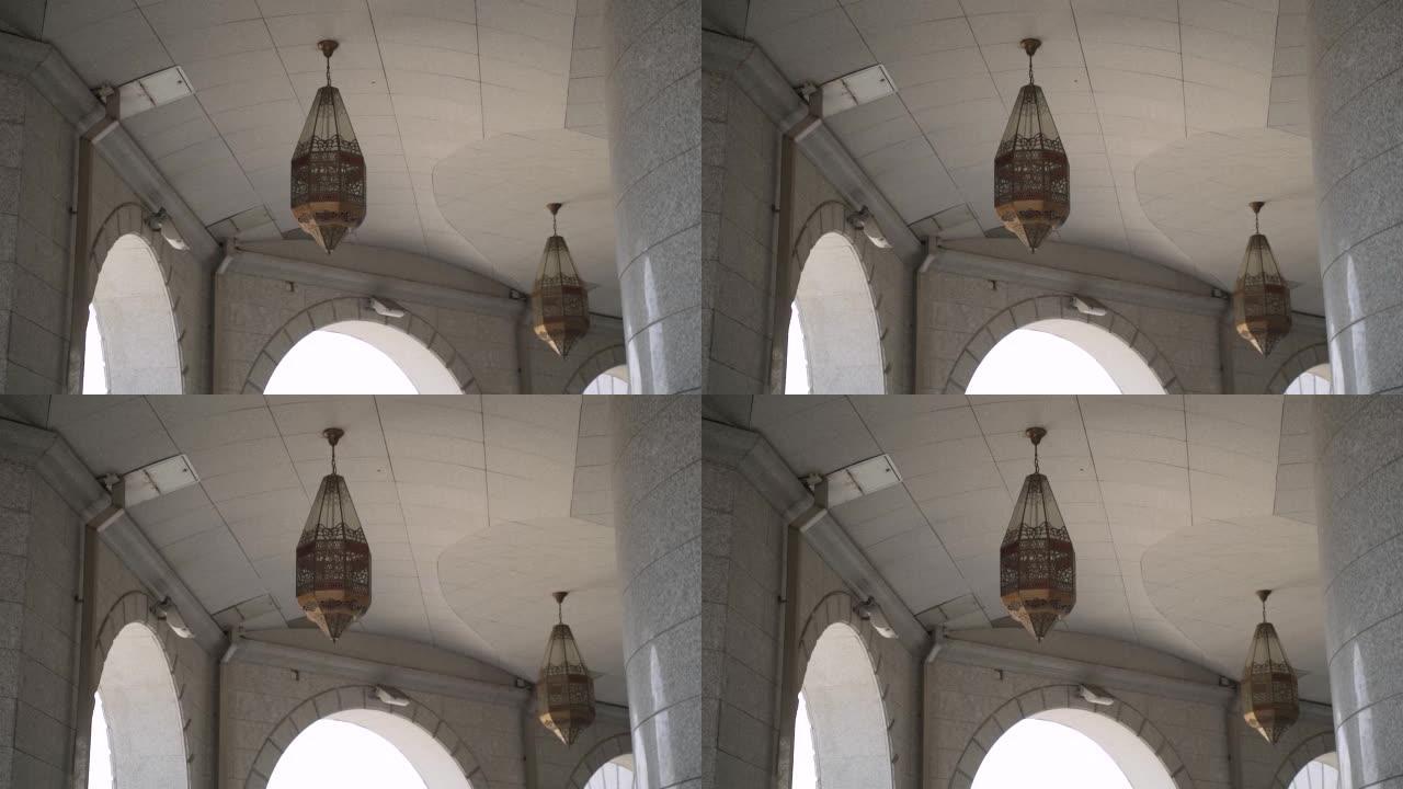 两盏铜图案的灯悬挂在敞开的拱门附近的瓷砖天花板上。
