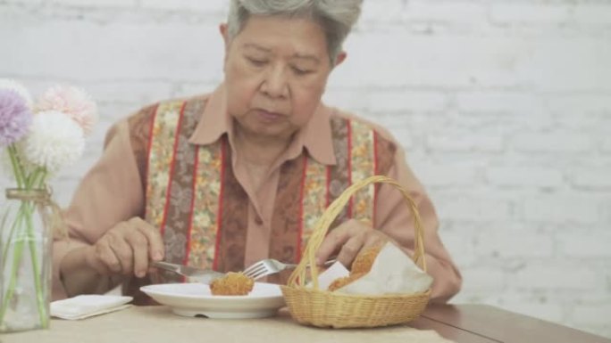 老年妇女吃脆皮土豆球炸丸子食品。成熟的退休生活方式