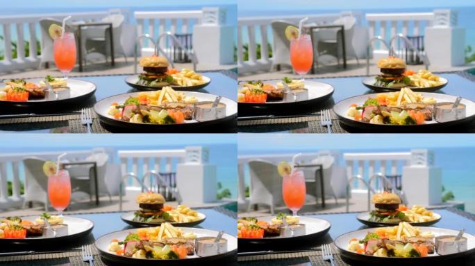 海景户外餐厅餐桌上的美味食物和热带鸡尾酒