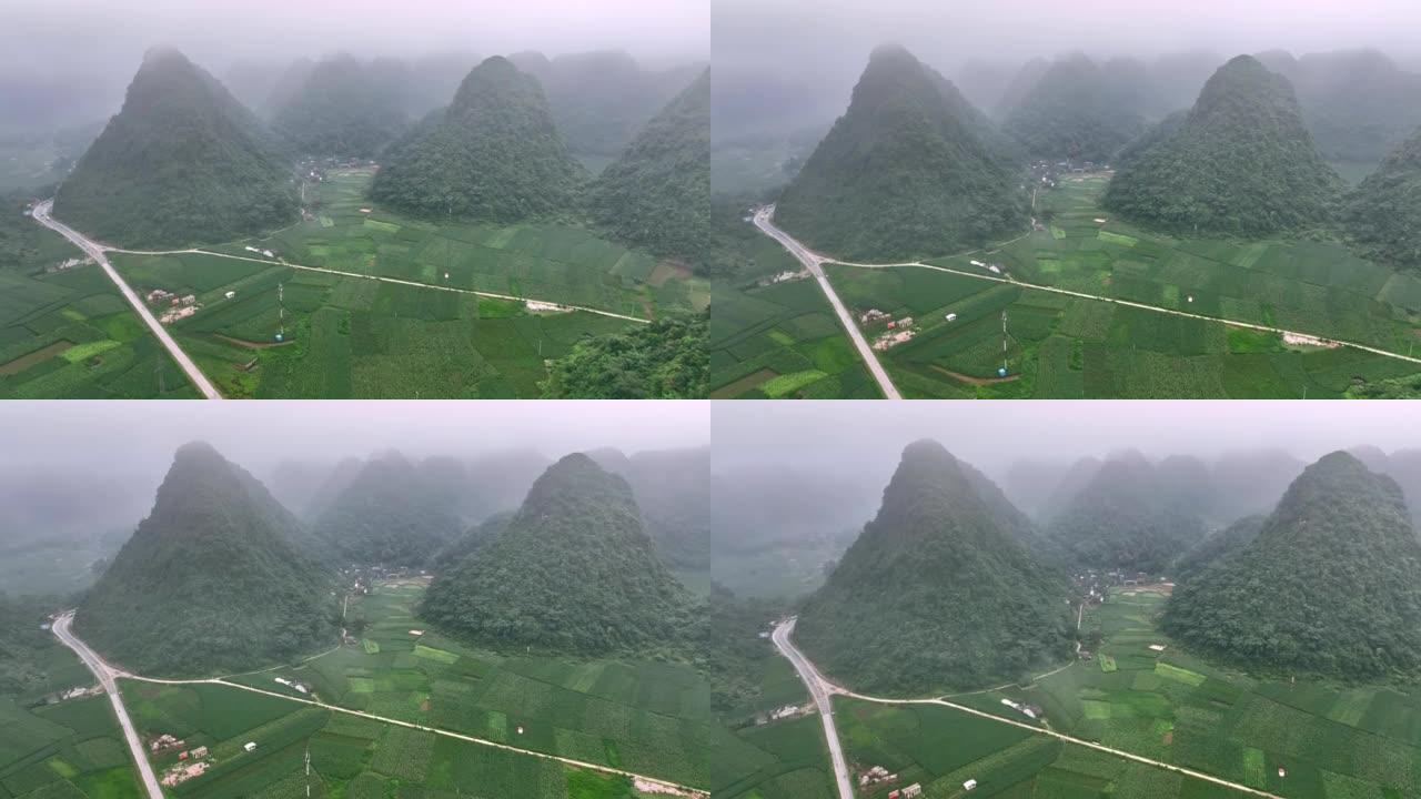 无人机在雾蒙蒙的雨林树木附近的雾蒙蒙的蜿蜒山路上飞行。电影镜头鸟瞰图雄伟的热带山脉景观。在越南北部