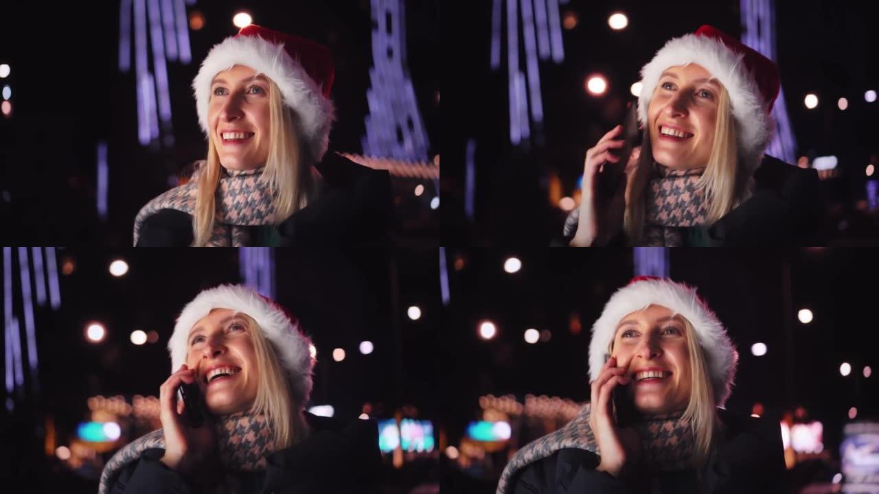一个戴着圣诞老人帽子在智能手机上聊天的女人是一个夜城。