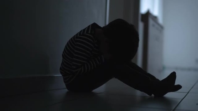 悲伤的孩子在家里遭受童年抑郁症的折磨。心理创伤的概念。一个小男孩在危机中捂着脸
