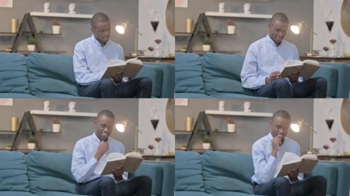 African Man Reading Book while Sitting on Sofa