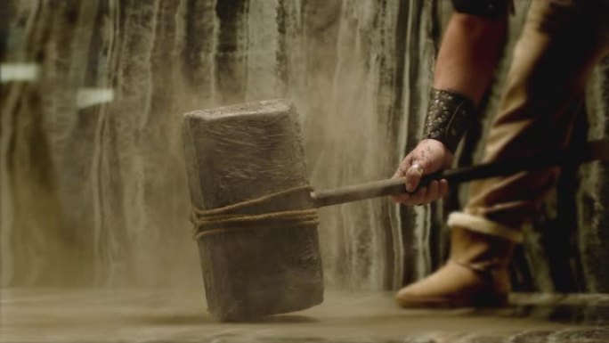 旧石器时代的大锤子撞击地板并喷洒灰尘。维京人用巨大的大锤砸地板。强度和耐用性概念。以200fps慢动