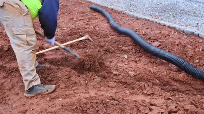 当大雨发生时，工人挖了一条沟渠，为雨水铺设排水管。