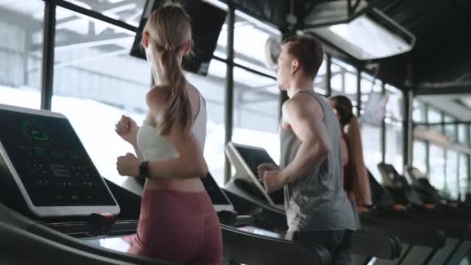 三个人在健身房的跑步机上散步和跑步。