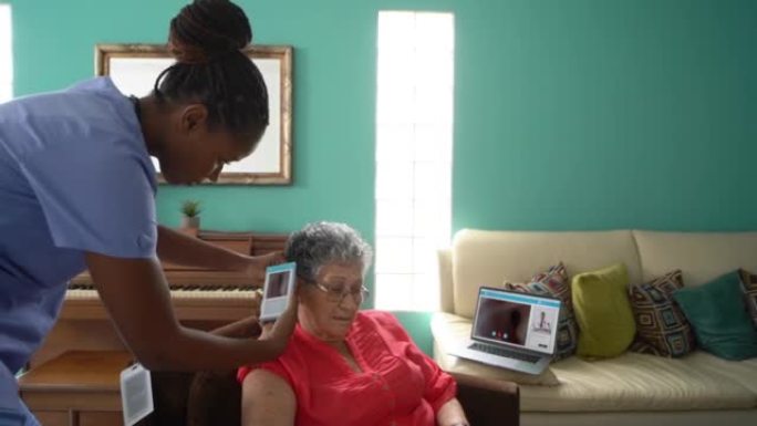 家庭护士用远程会诊装置检查老年妇女的耳朵