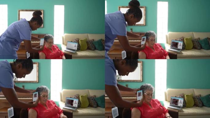 家庭护士用远程会诊装置检查老年妇女的耳朵