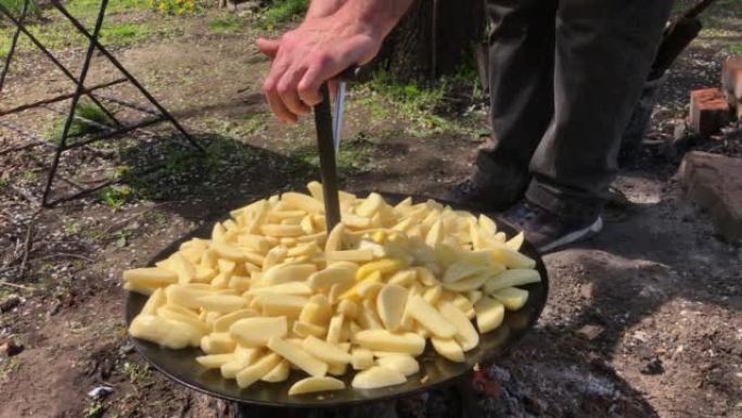 切成薄片的生土豆，在户外的大型自制烤架上烤。