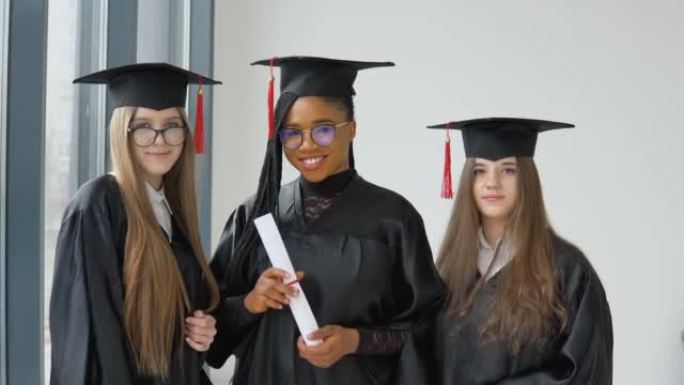 三名不同种族的女学生手里拿着文凭。受过高等教育的大学女毕业生