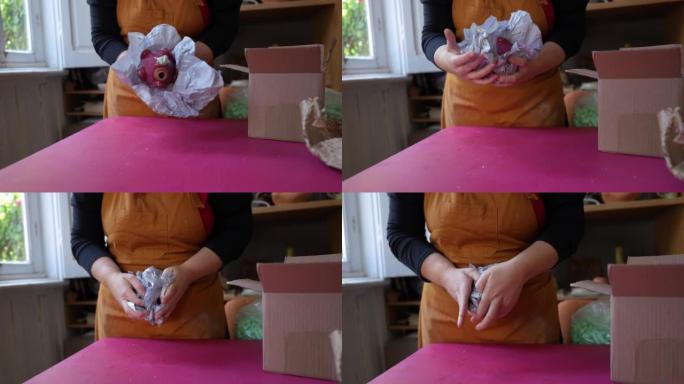 女人用纸仔细包装陶瓷片