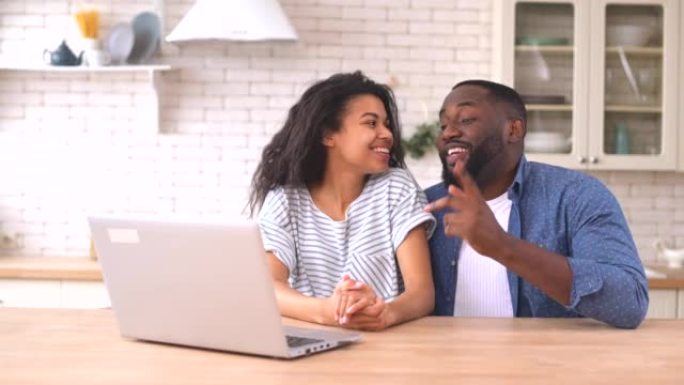 快乐的非裔美国人夫妇在恋爱中使用笔记本电脑进行视频连接