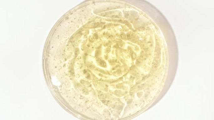 在Petri玻璃碗中带有气泡的透明黄色化妆品凝胶液。宏丸血清、乳膏、透明质酸。有机化妆品，药品。概念