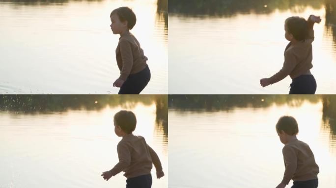 小男孩在水里扔石头。慢动作