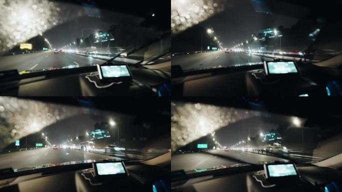 汽车的观点在雨中夜间行驶，雨刮器在高速公路上打开
