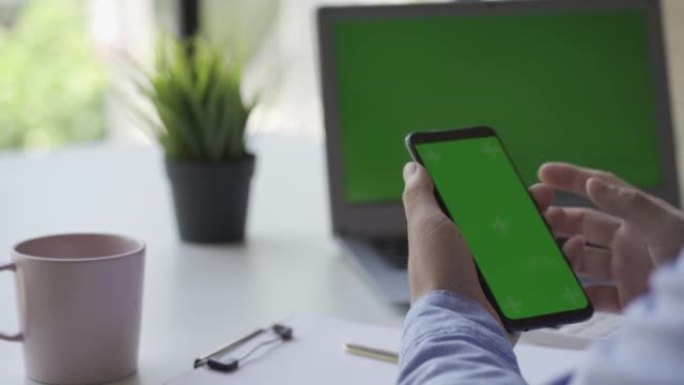 移动智能手机与绿屏和一个人的手的特写，并使用现代智能手机在线。学习和查找信息