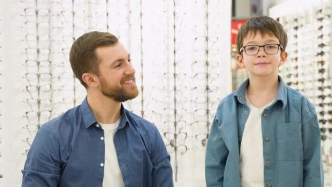 和父亲在光学店戴新眼镜的小男孩。眼科概念