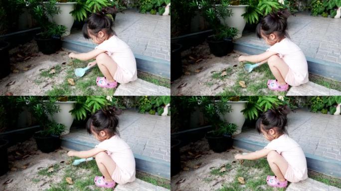 小女孩试着在地上种草或植物，在草地上倒些土，晚上在家玩耍。