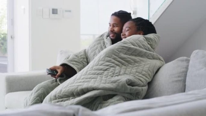 一对年轻夫妇在家一起放松。快乐的男人和女人在沙发上盖着毯子