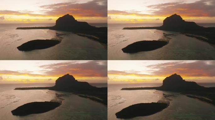 勒莫恩山后面太阳升起的风景鸟瞰图。毛里求斯日落美景，前景是海滩和岩石。