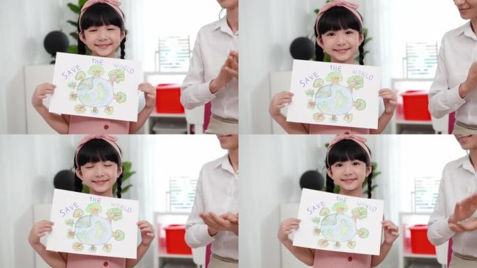 可爱的亚洲六岁女孩在拯救世界的主题中展示并拿着她的画，她画了球形的全球覆盖物，上面覆盖了许多绿色的森