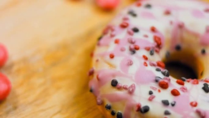用糖果装饰的粉色甜甜圈。微距和滑块拍摄。釉面甜品。面包店和食品概念。各种彩色甜甜圈。4K，UHD巧克